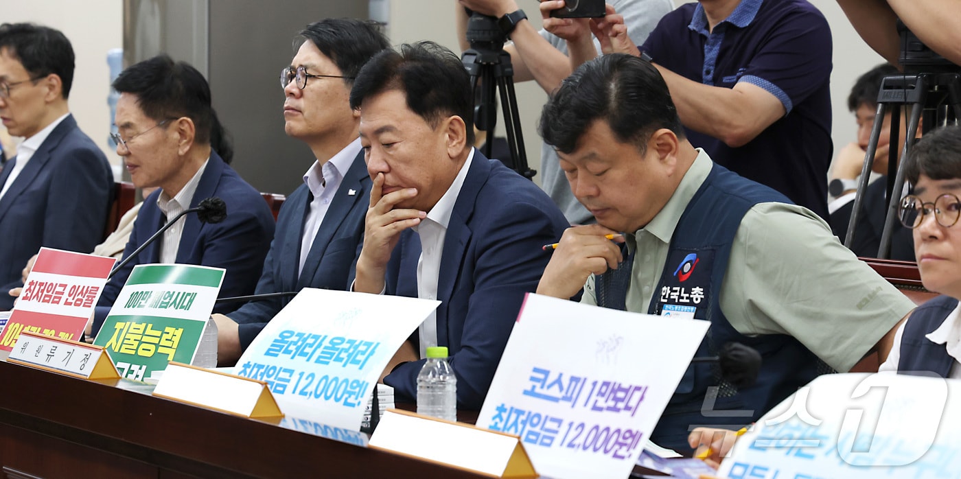 류기정 사용자위원과 류기섭 근로자위원이 23일 세종시 정부세종청사 최저임금위원회에서 열린 2027년도 최저임금위원회 8차 전원회의에서 최저임금 1만2000원 요구와 지불능력 고려 손팻말을 게시하고 본격적인 논의를 시작하고 있다. (사진은 기사 내용과 무관함) 2026.6.23 ⓒ 뉴스1 자료 사진