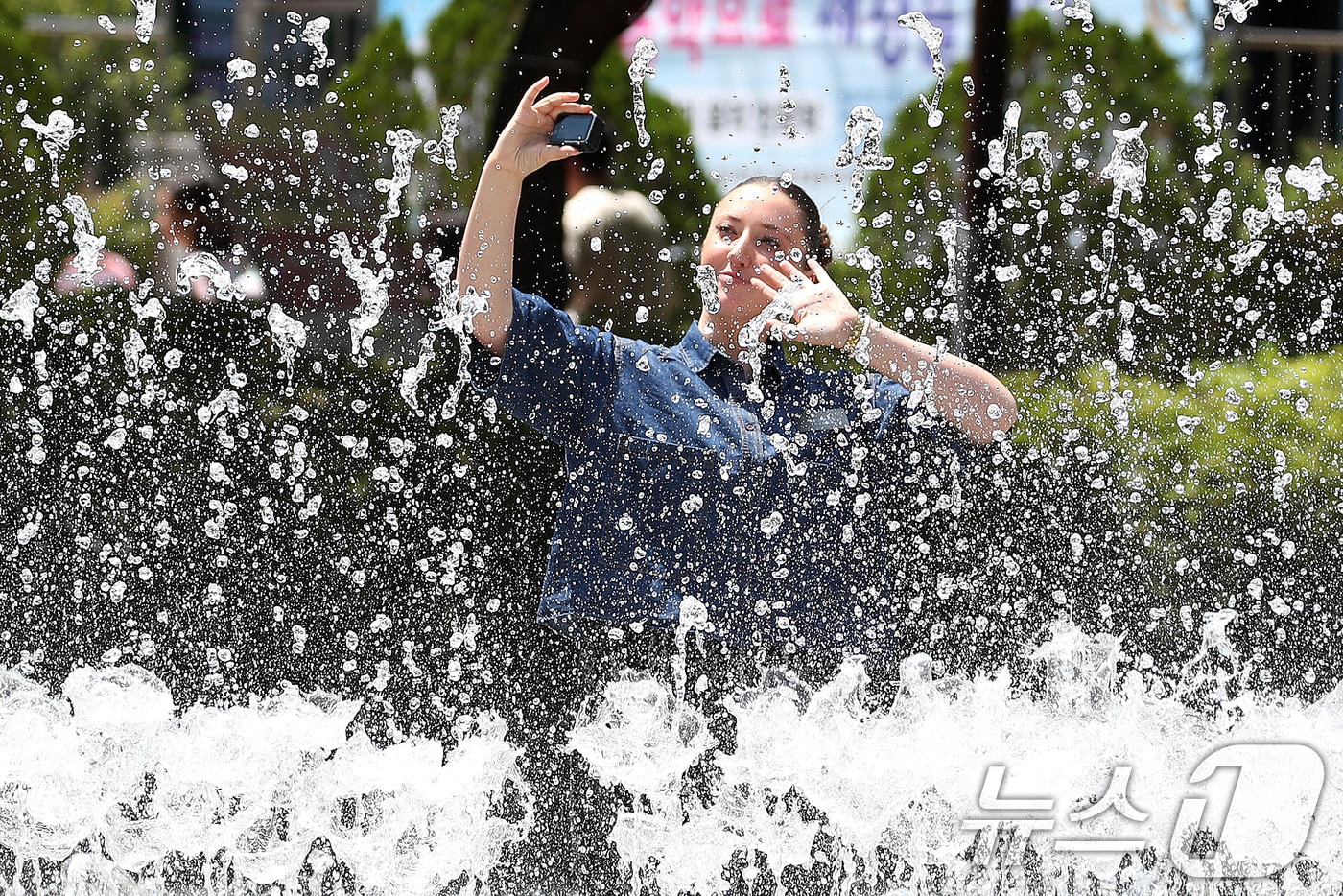 구름 사이로 해가 나오며 더위가 찾아온 26일 오후 한 외국인이 바닥분수 물줄기 사이를 오가며 기념사진을 찍고 있다. 2026.6.26 ⓒ 뉴스1 공정식 기자