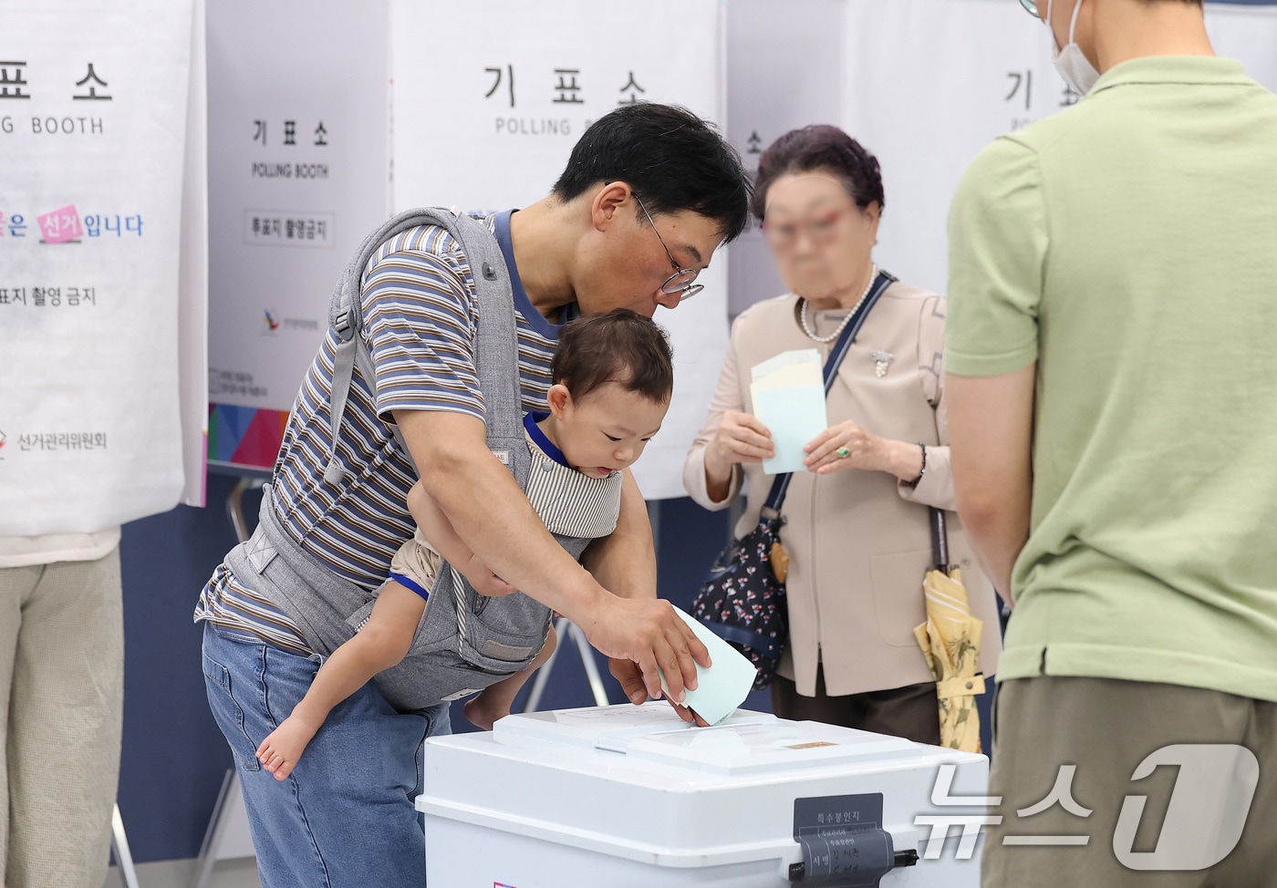 제9회 전국동시지방선거일인 3일 서울 강남구 강남구청에 마련된 삼성2동 제5투표소에서 한 시민이 아기를 아기띠에 안은 채 소중한 한 표를 행사하고 있다. 2026.6.3 ⓒ 뉴스1 박지혜 기자