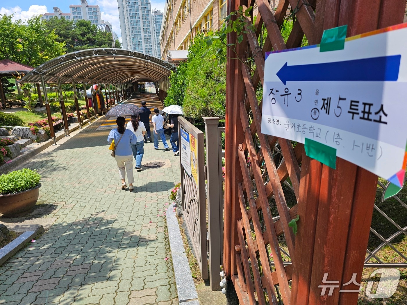 일 김해 율하초등학교에 마련된 장유3동 제5투표소로 양산을 쓴 유권자들이 걸어가고 있다.2026.6.3/뉴스1 박민석기자