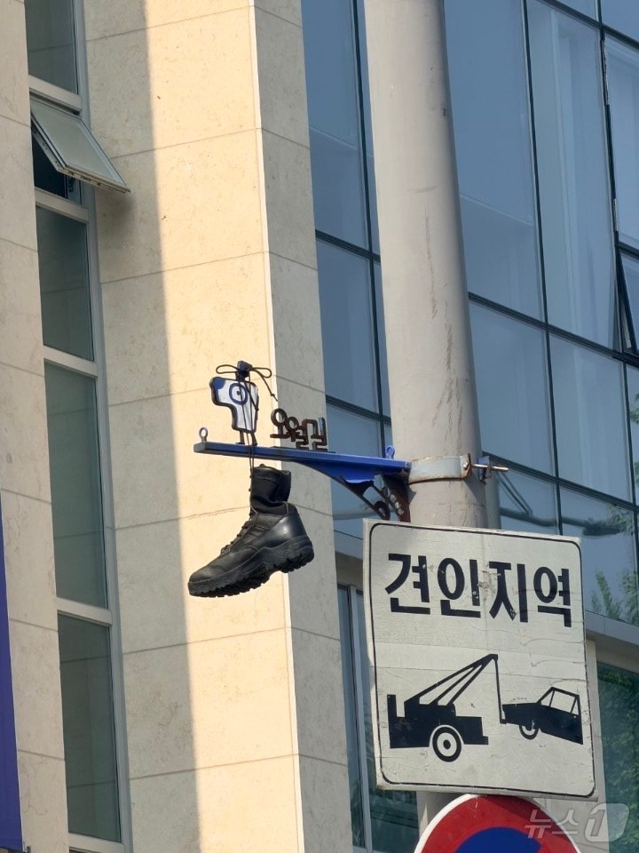 30일 광주 동구 대인동의 한 교차로에 설치된 오월길을 안내하는 표지판에 군화가 걸려 있다. 5.18기념재단과 광주시는 군화를 수거하는 한편 누가, 어떤 의도로 군화를 걸었는지 조사에 착수했다. (5·18기념재단 제공. 재판매 및 DB금지) 2026.6.30 ⓒ 뉴스1