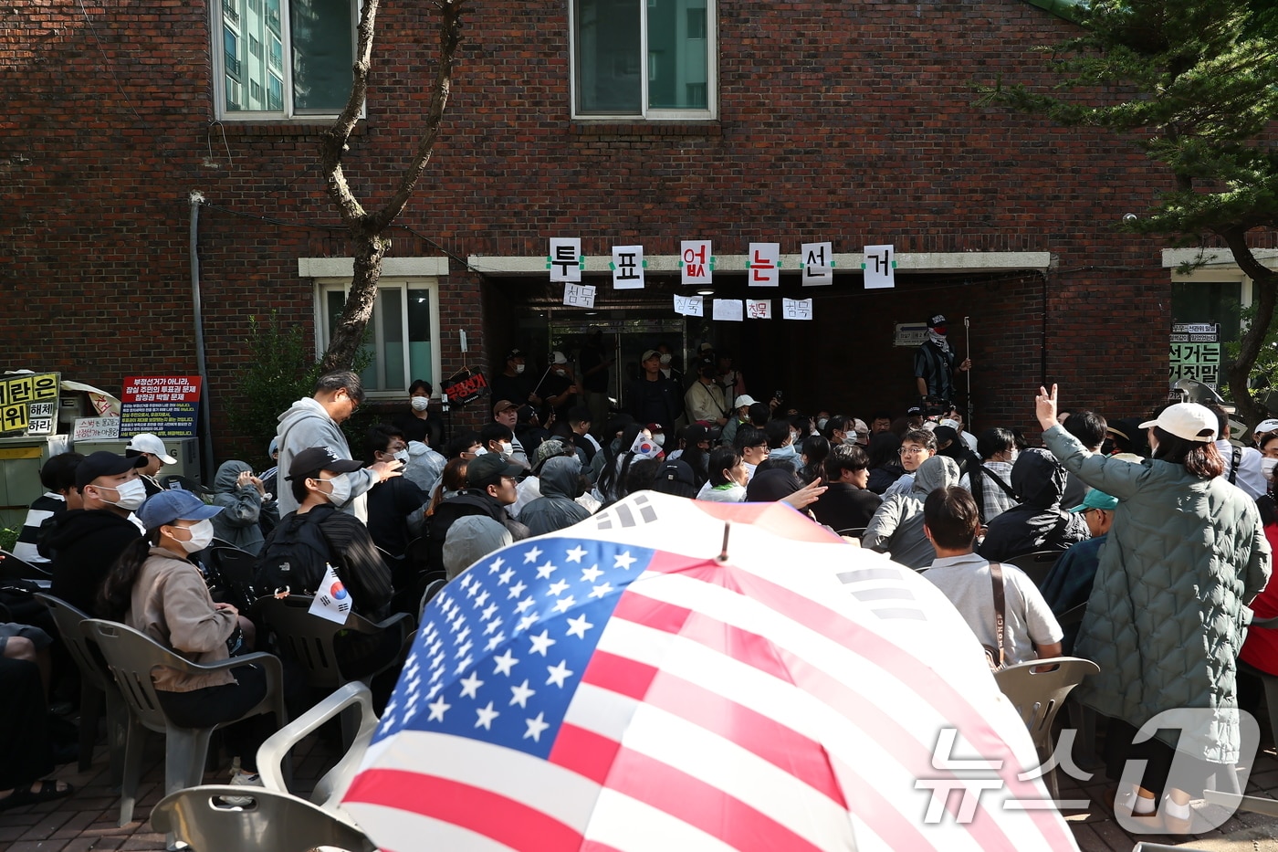 5일 '투표용지 부족' 사태가 발생한 서울 송파구 잠실7동 제2투표소 앞에서 집회 참가자들이 투표함 반출을 막기 위해 경찰들과 대치하고 있다. 2026.6.5 ⓒ 뉴스1 김도우 기자