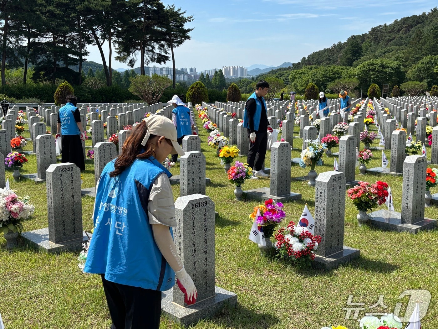 대전자생한방병원 임직원과 대전자생봉사단원들이 국립대전현충원 묘역에서 비석을 정비하고 태극기를 꽂고 있다.(자생의료재단 제공)