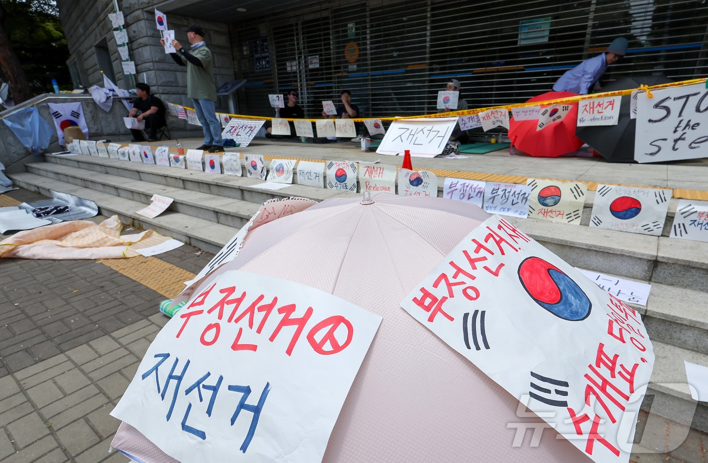 제9회 전국동시지방선거 투표용지 부족 사태에 반발한 시민들이 9일 서울 송파구 올림픽공원 핸드볼경기장에 설치된 개표소 앞에서 재선거를 촉구하며 구호를 외치고 있다. 2026.6.9 ⓒ 뉴스1 김성진 기자