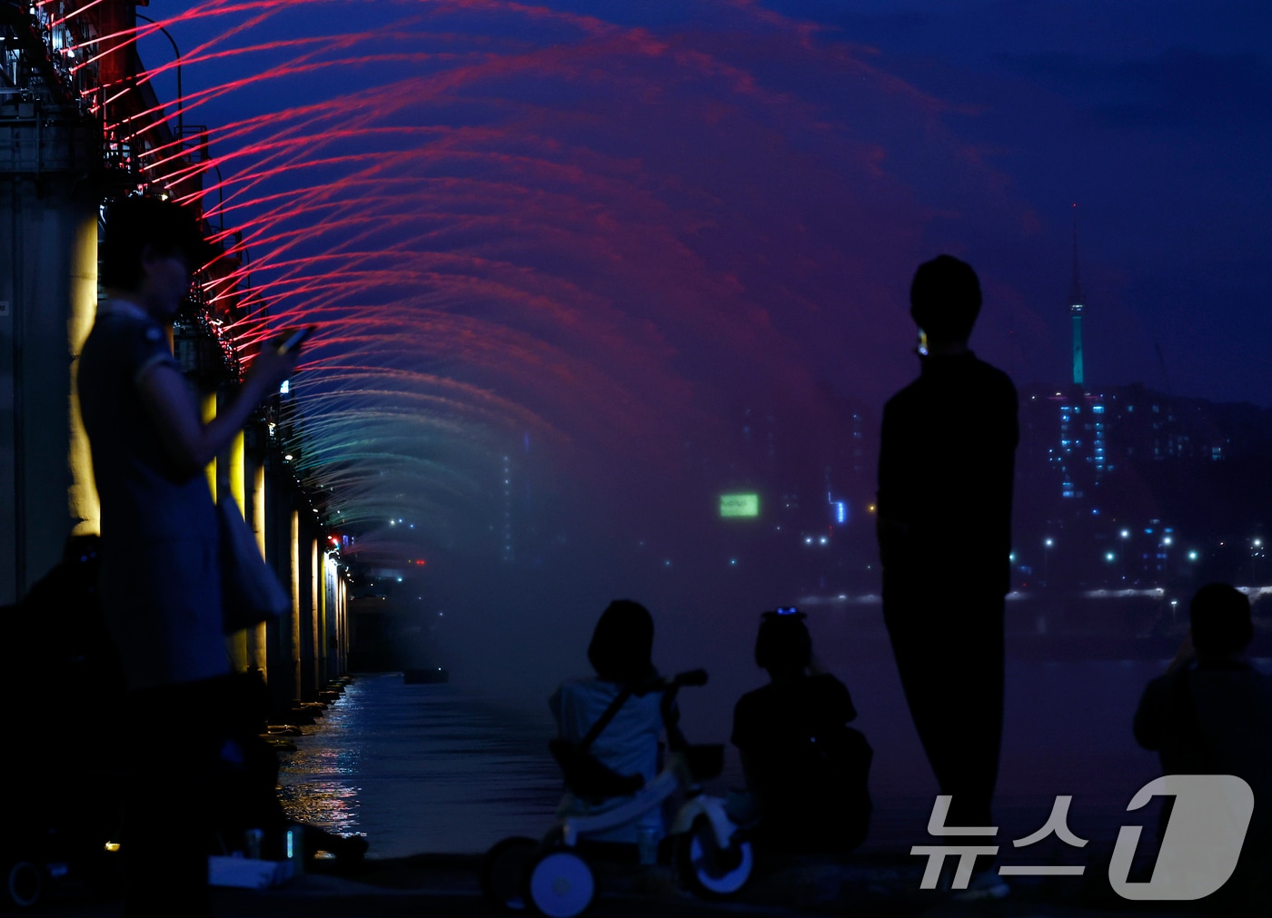 전국 대부분 지역에 폭염특보가 이어지며 낮 최고기온이 37도까지 오르는 찜통더위가 이어진 12일 오후 서울 서초구 신반포로 반포한강공원을 찾은 시민들이 시원한 물줄기를 내뿜는 반포대교 달빛무지개분수를 바라보며 더위를 식히고 있다. 2026.7.12 ⓒ 뉴스1 박정호 기자