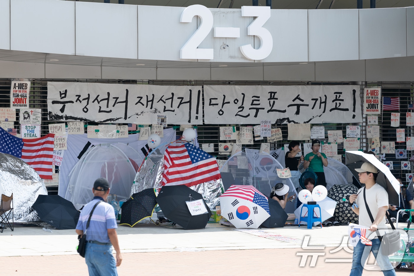 6·3지방선거 이후 한 달 넘게 개표소 봉쇄 시위가 계속되고 있는 지난 17일 서울 송파구 올림픽공원 핸드볼경기장 입구 앞을 시민들이 지나고 있다. 2026.7.17 ⓒ 뉴스1 안은나 기자