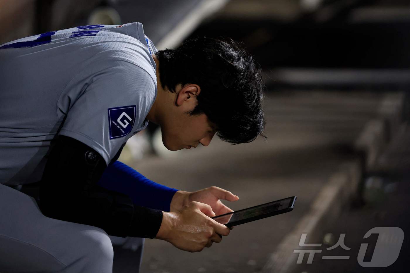 더그아웃에서 태블릿 PC를 보고 있는 오타니. ⓒ AFP=뉴스1