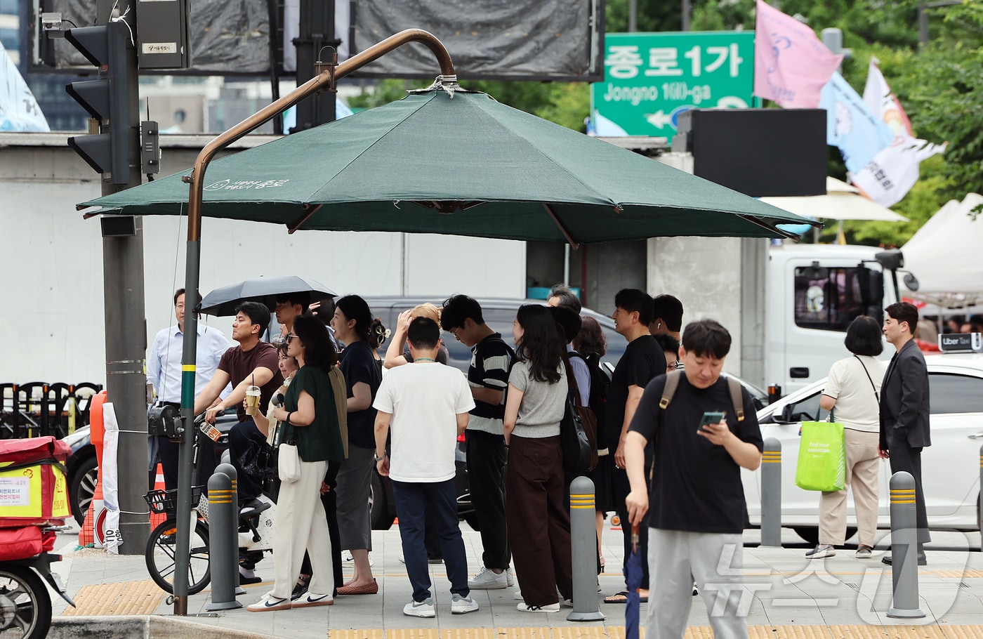절기상 본격적인 더위가 시작된다는 소서(小暑)이자 무더운 날씨를 보인 7일 오후 서울 종로구 광화문사거리에 설치된 대형 그늘막에서 시민들이 신호를 기다리며 햇빛을 피하고 있다. 2026.7.7 ⓒ 뉴스1 김진환 기자