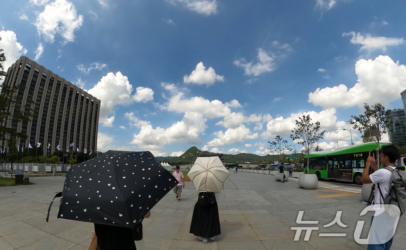 25일 서울 종로구 광화문광장에서 관광객들이 양산을 쓰고 이동하고 있다.  2026.8.25 ⓒ 뉴스1 김명섭 기자