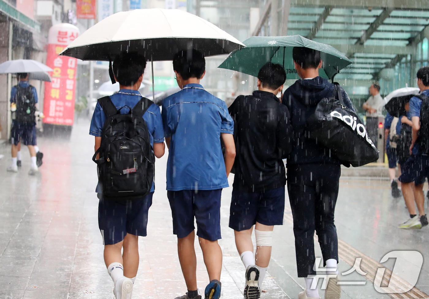 27일 오후 대구 수성구 달구벌대로 담티고개 인근에 천둥번개를 동반한 비가 내리자 하굣길 학생들이 우산으로 비를 피하며 발걸음을 재촉하고 있다. 2026.8.27 ⓒ 뉴스1 공정식 기자