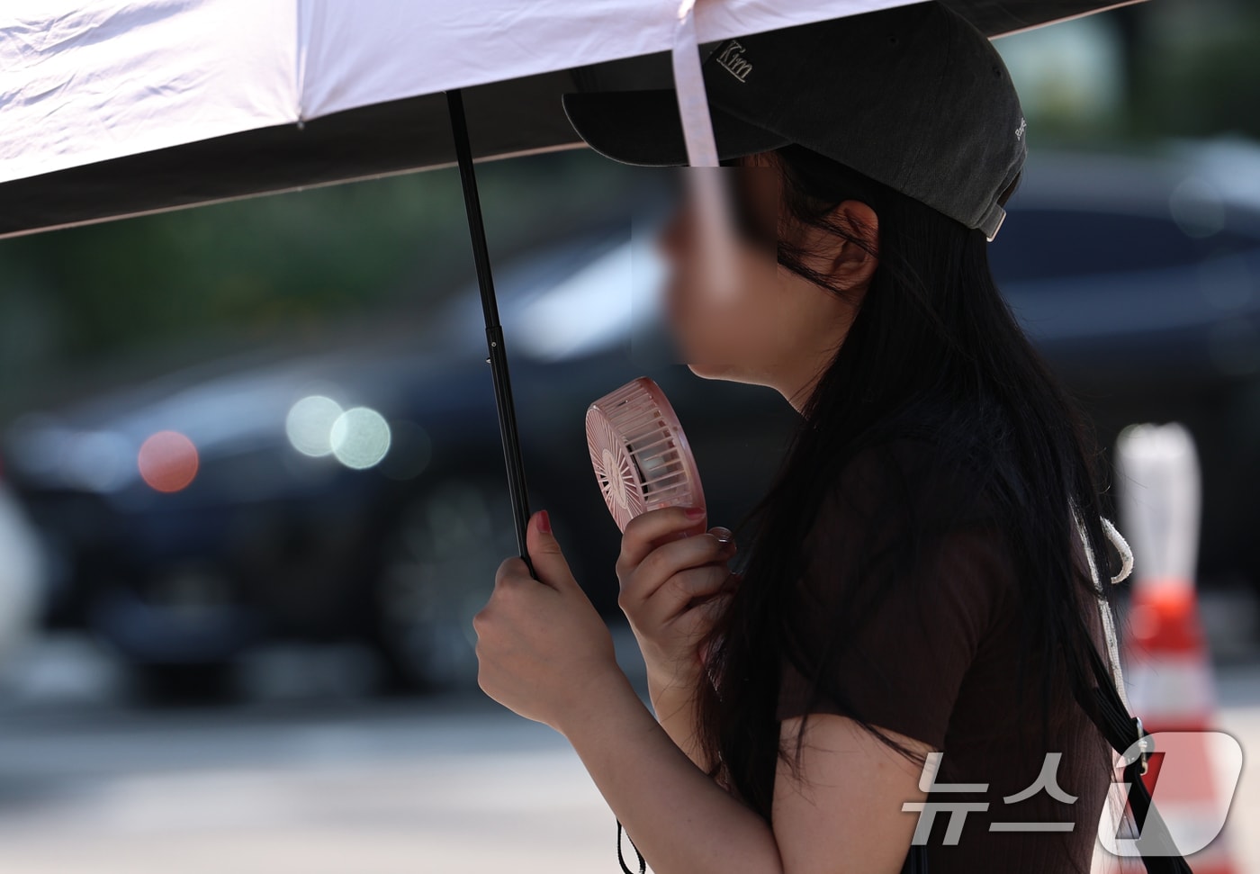 강원 일부 지역을 제외한 전국에 폭염특보가 내려진 3일 오전 서울 광화문 네거리에서 한 시민이 양산과 휴대용 선풍기로 더위를 식히고 있다. 2026.8.3 ⓒ 뉴스1 구윤성 기자