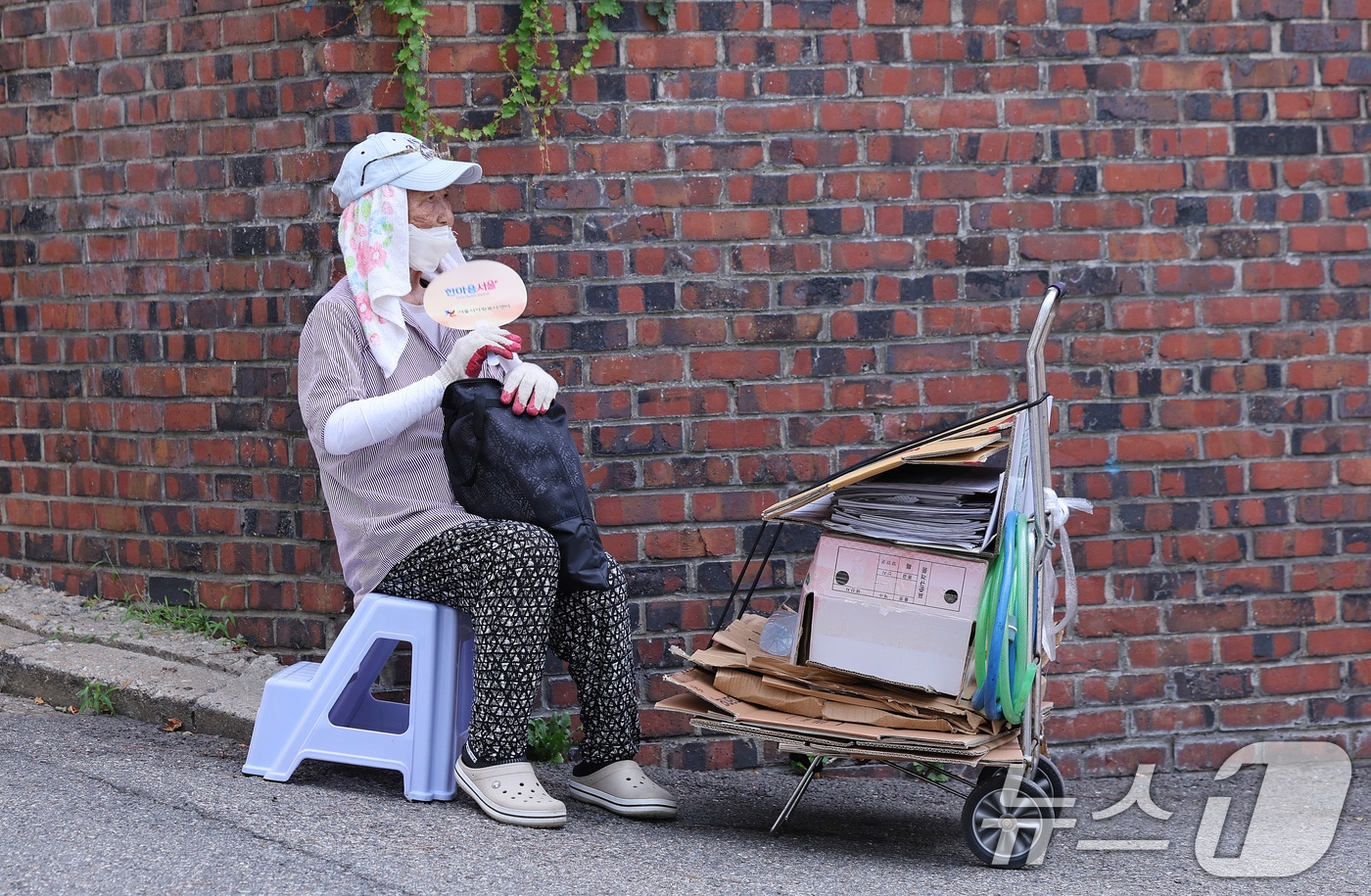 4일 서울 용산구 효창동 일대 골목에서 폐지를 수집하는 노인이 서울시에서 지급한 폭염 예방 물품으로 더위를 식히고 있다. 2026.8.4 ⓒ 뉴스1 박지혜 기자