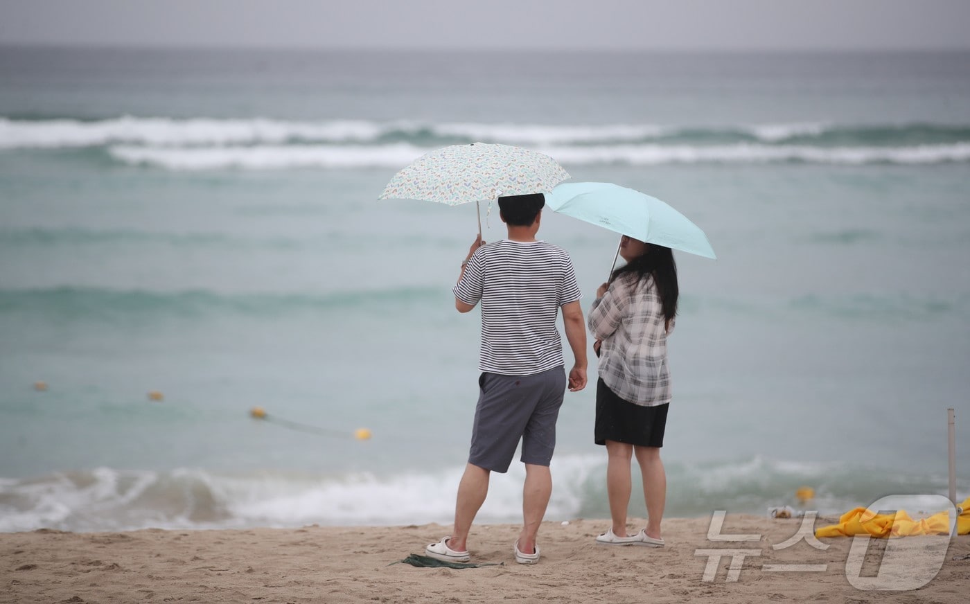제주시 조천읍 함덕해수욕장에서 우산을 쓴 관광객들이 파도가 이는 바다를 바라보고 있다. 2026.8.9 ⓒ 뉴스1 강승남 기자